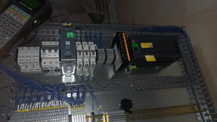 Vista cenital del montaje interno de un tablero: PLC, switch de red, fuente de 24 V, protecciones y borneras numeradas sobre riel