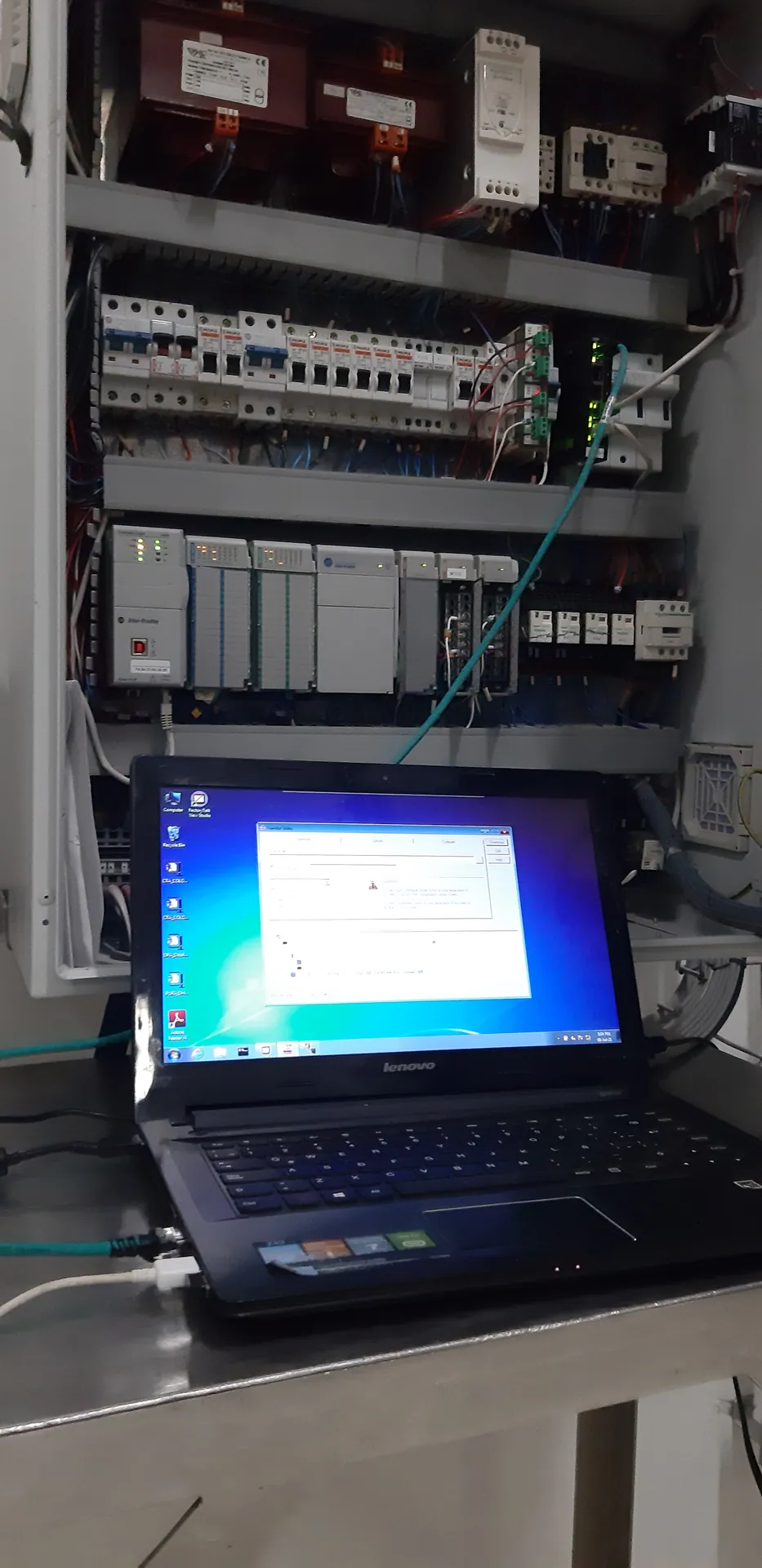 Tablero con PLC modular, protecciones y borneras, con un portátil conectado durante la programación