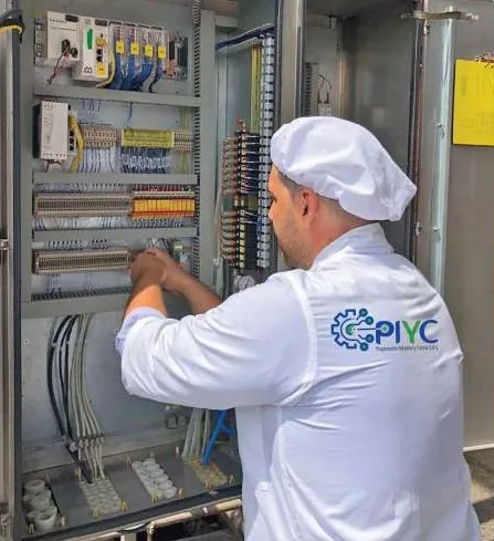Técnico con la chaqueta de PIYC interviene el cableado de un tablero de control en acero inoxidable